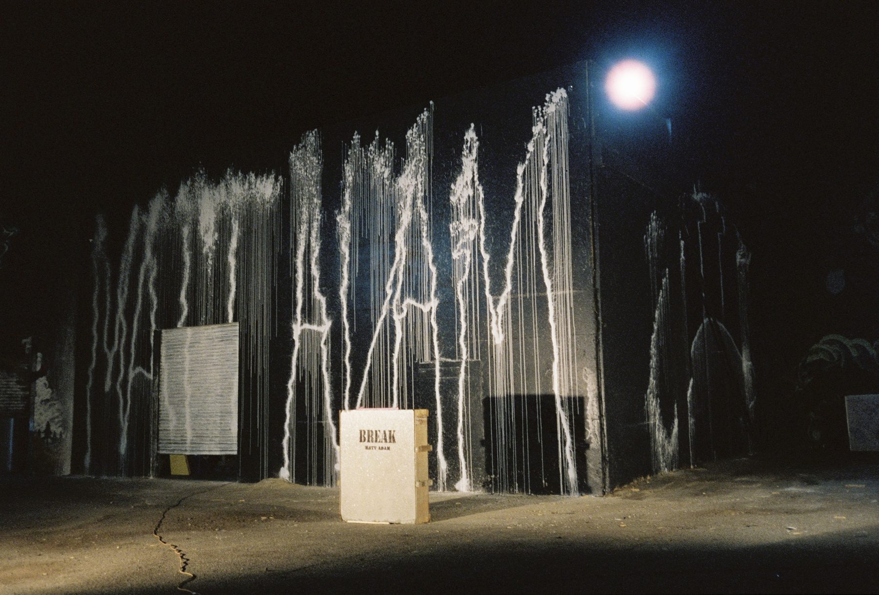 Matt Adam "break" warehouse show, white fire-extinguisher paint marks across a black wall at night