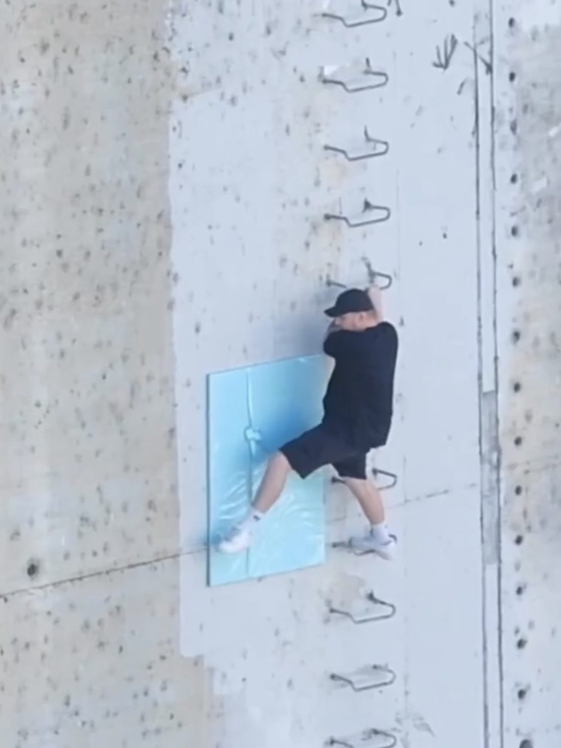 Aerial view of Matt Adam placing a blue-wrapped Unwrap and Steal artwork on a concrete embankment