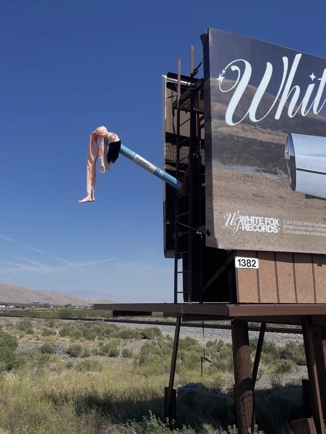 Matt Adam Skinny series, deflated doll impaled on a giant Ozempic needle mounted on a desert billboard near Coachella