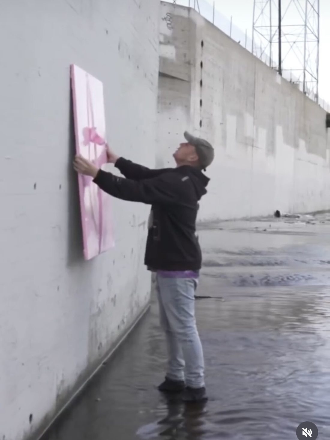 Matt Adam installing a pink-wrapped Unwrap and Steal artwork on a Los Angeles River wall
