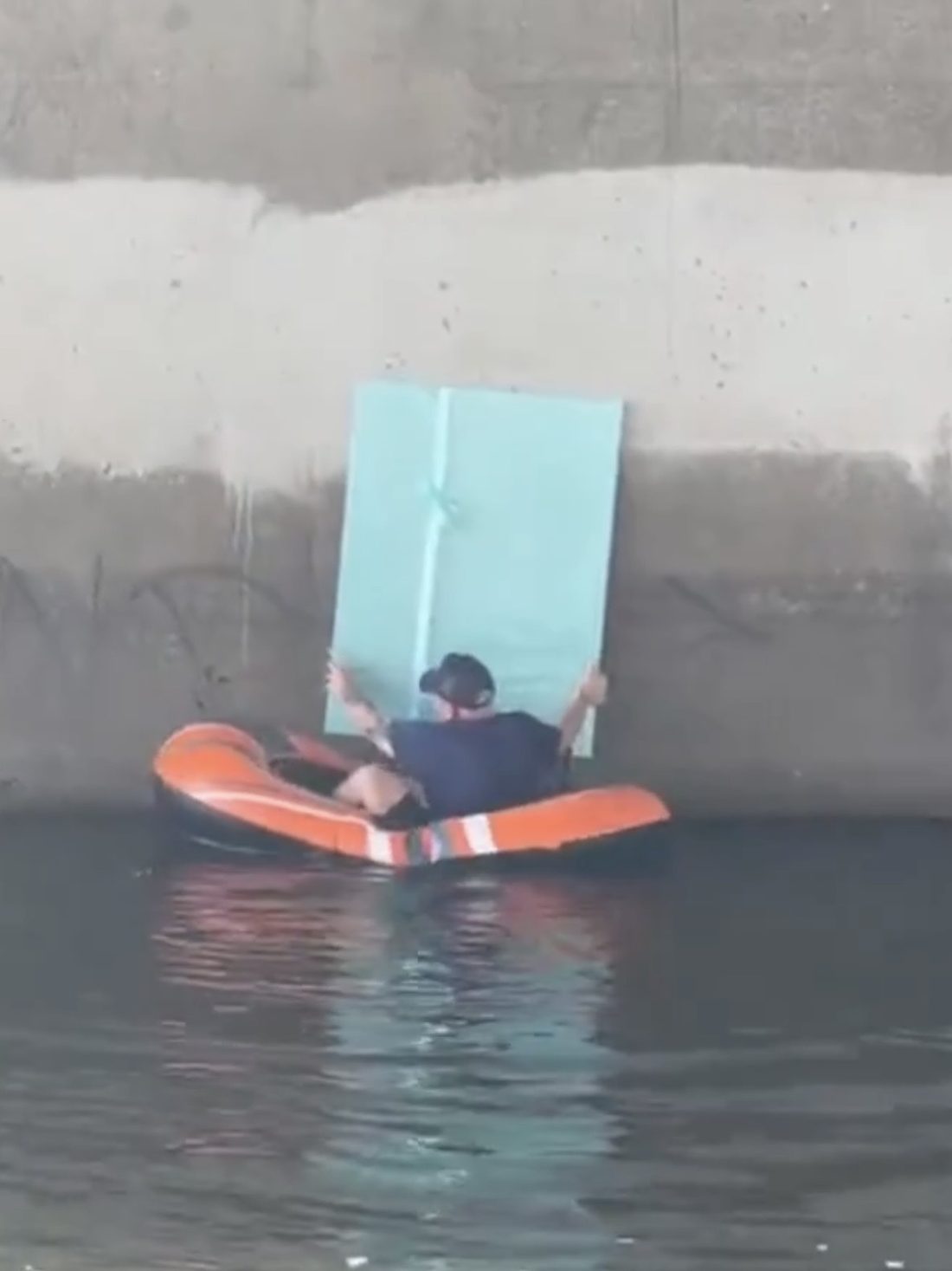 Matt Adam hiding a wrapped Unwrap and Steal artwork from an inflatable raft on the water